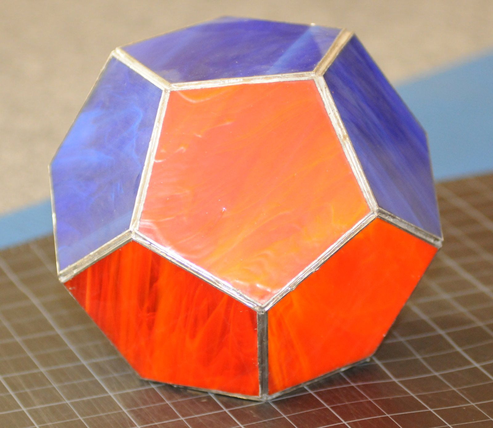 the Platonic Solid Dodecahedron made of blue and orange pentagons of stained glass