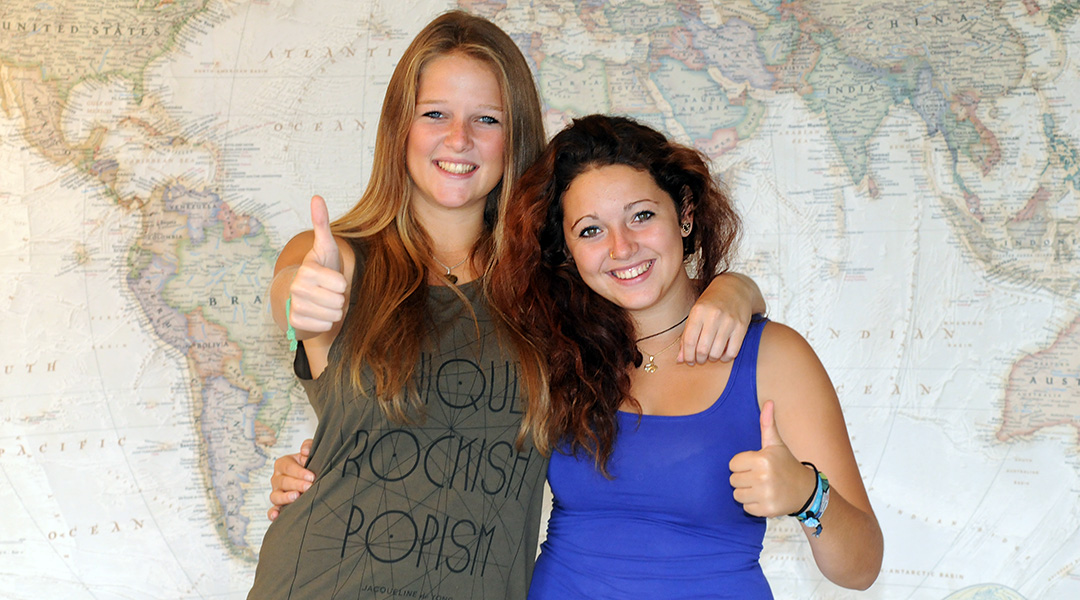 two women standing in front of a world map