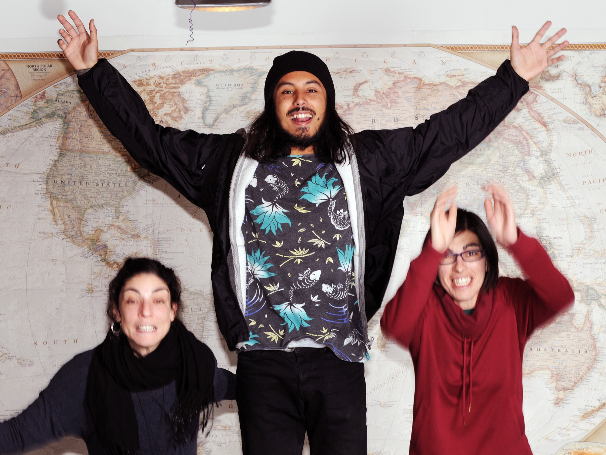 3 people jumping in front of a world map
