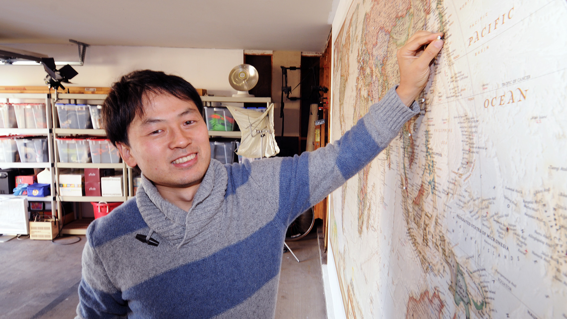 photo of Tomo Ono pushing a "Country #25" pin into a world map. His pin is at Yokohama, Japan