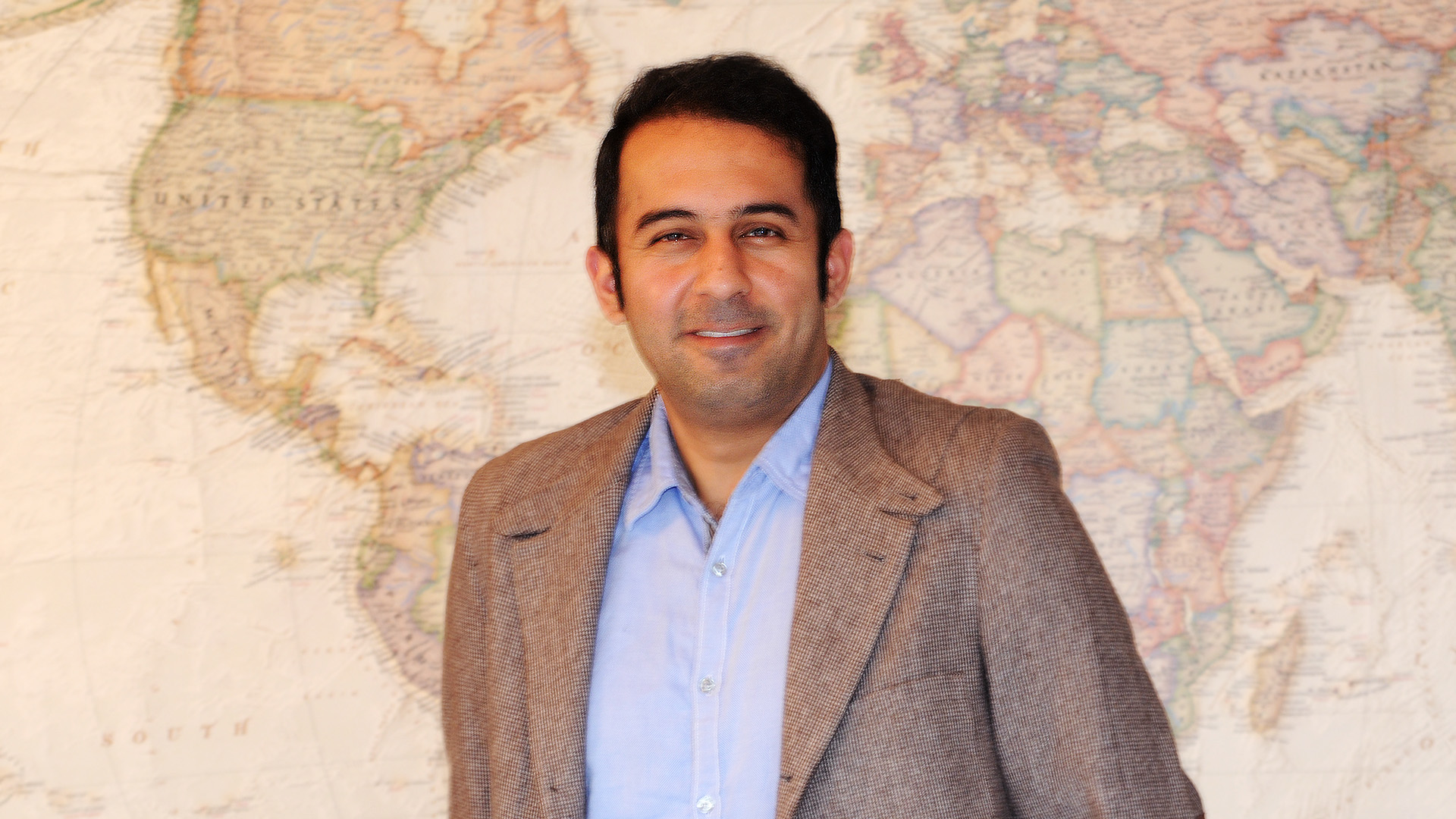 photo of Amir Yazdanbakhsh standing in front of a world map