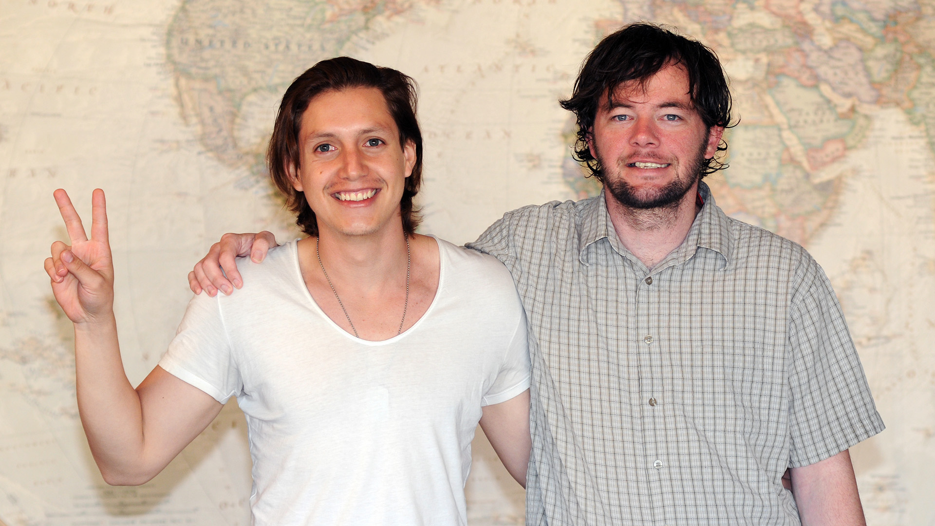 Christian and Matt standing together in front of a large world map