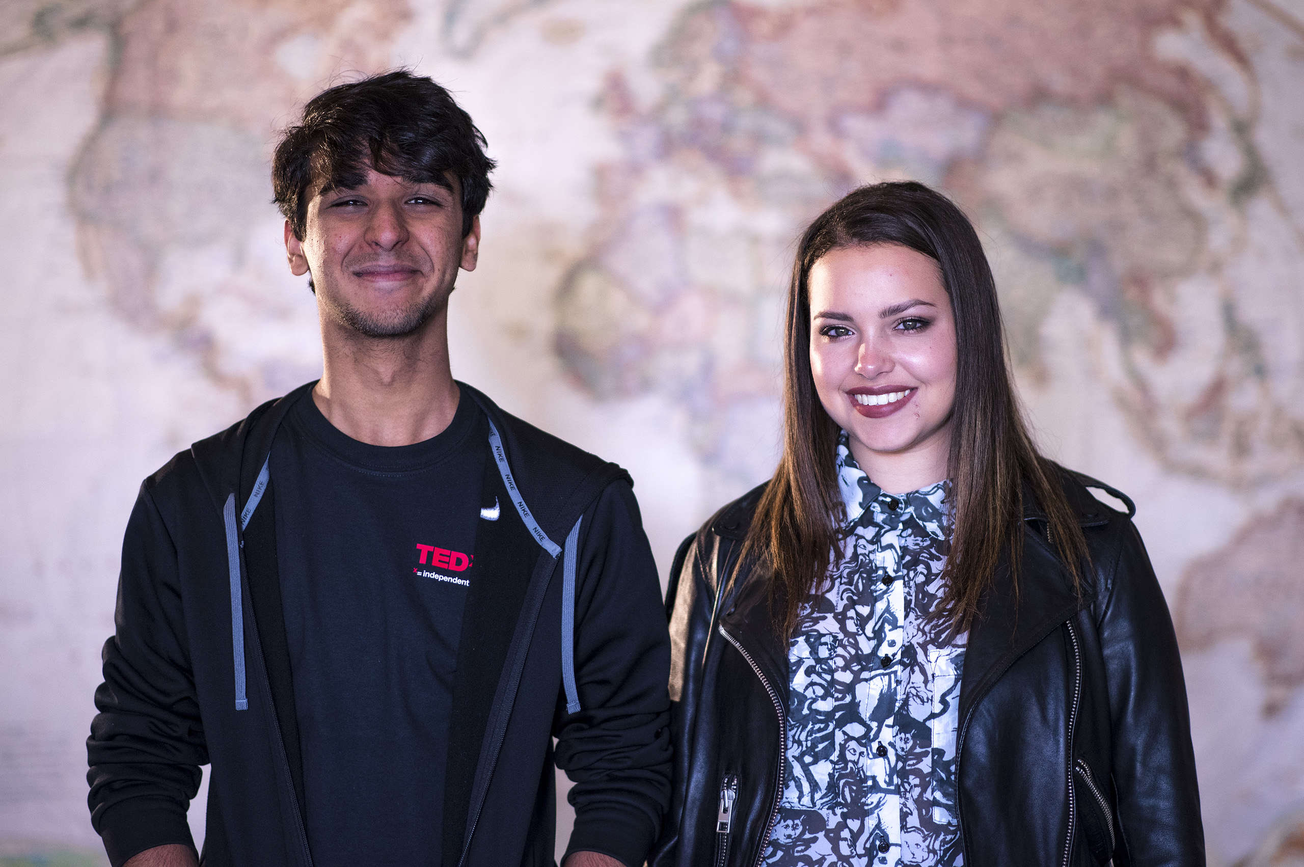 Mihir Kathpalia and Allison Bouganim dressed in black and standing in front of a large world map