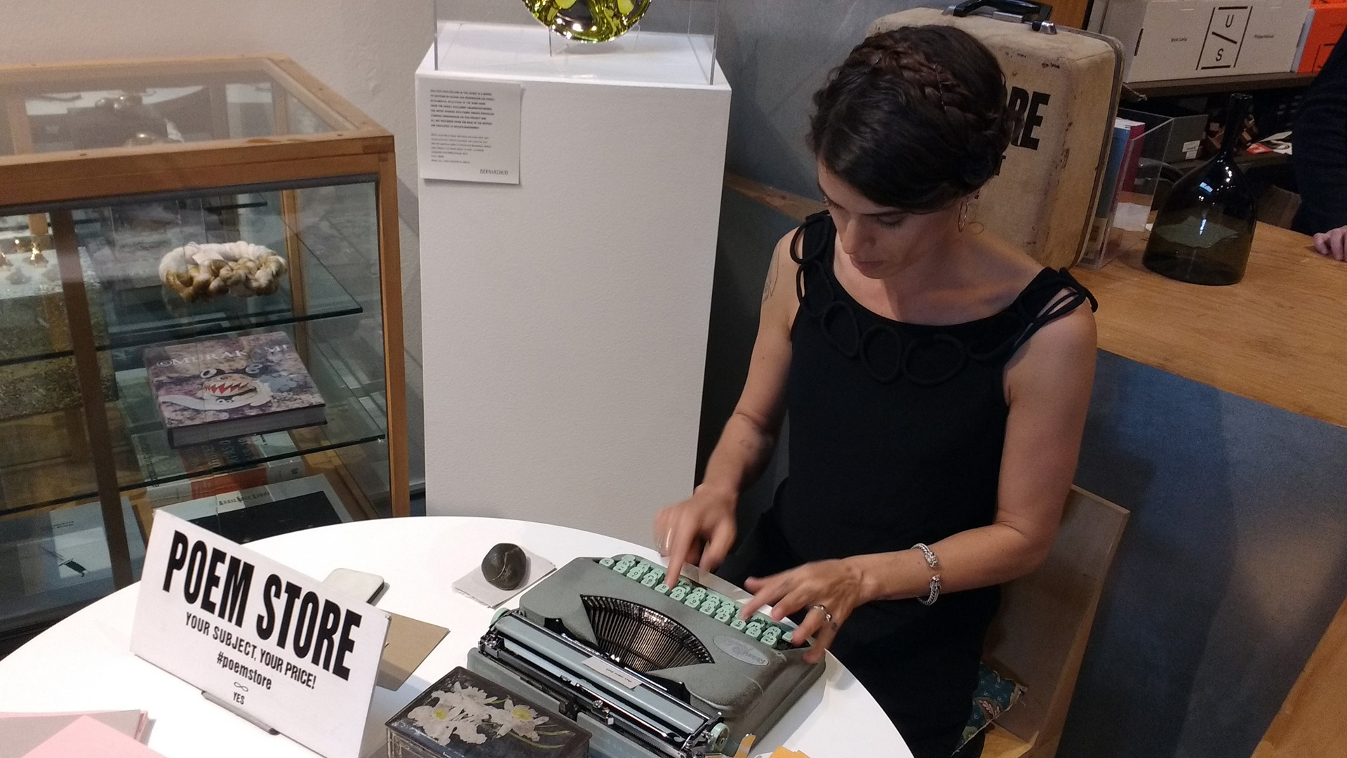 Jacqueline Suskin in the bookstore at The Geffen Contemporary at MOCA during the LA Art Book Fair. Suskin is typing a poem on a tiny piece of newsprint on an old, manual typewriter