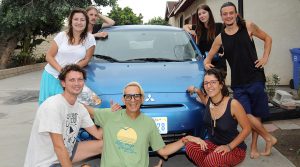 photo of 7 people grouped around a compact car