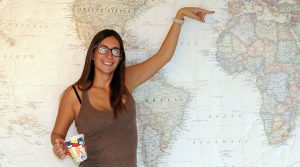 Larra Royo standing in front of a map of the world and pointing to Spain