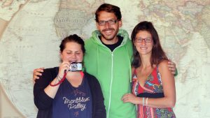 three people standing in front of a world map