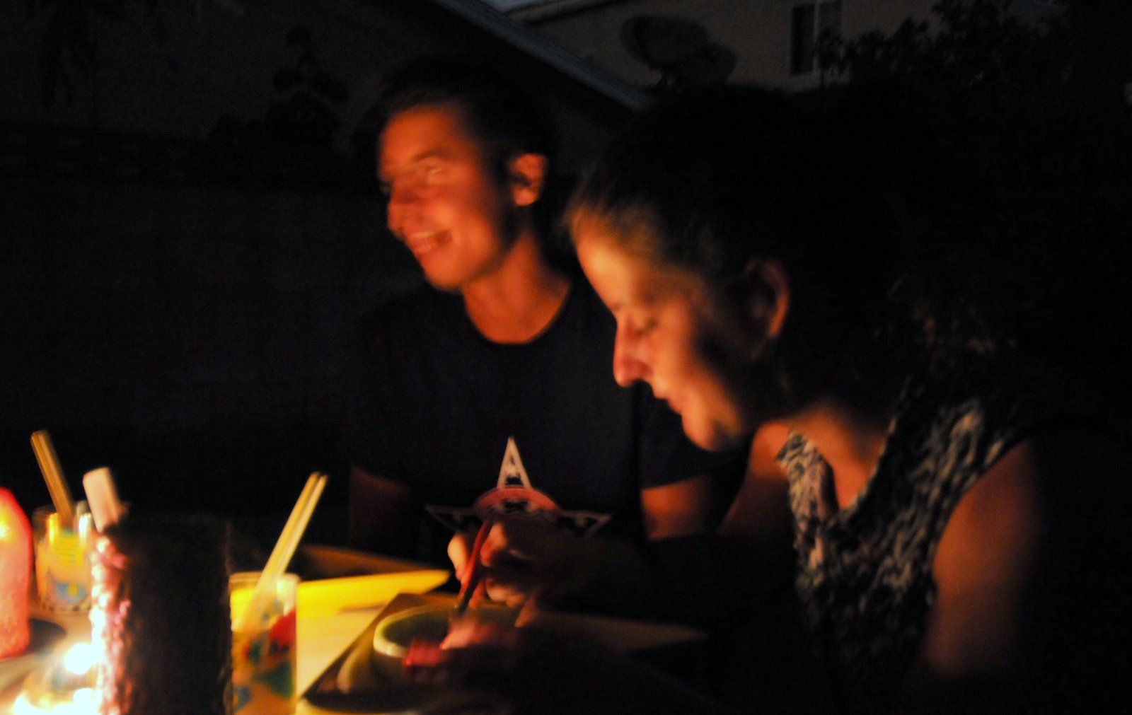 Akos & Eszter eat dessert in the backyard. Available-light photo illuminated by candles