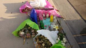 Candles and flowers by the side of the street.