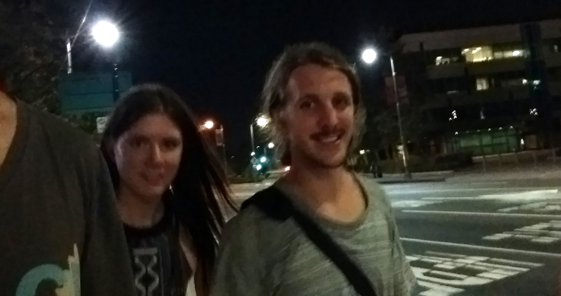 Two people walking down the street at night.