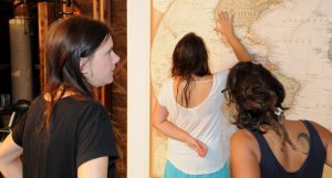 3 people looking at a 10 foot wide world map