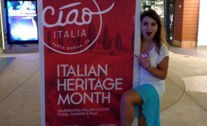 Elena posing with a large banner that reads "Italian Heritage Month"