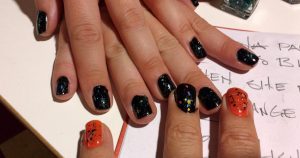 closeup of Elena & Glenn's hands with Orange and Black nail polish and glitter