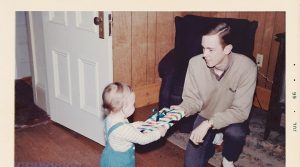 Vintage 1966 photo of a young father giving a present to his young child