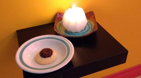 A candle and a cookie on a small shelf