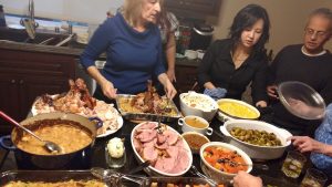 a table filled with foods and several people preparing them
