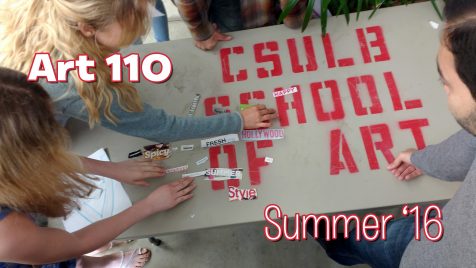 Students arranging "words" torn from magazines on a large table that has the stenciled words "CSULB SCHOOL OF ART" on it's surface. CSULB School of Art, Dutzi Gallery, May 2016.