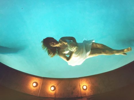 a woman floating, unconscious (simulated) in a pool and holding flowers