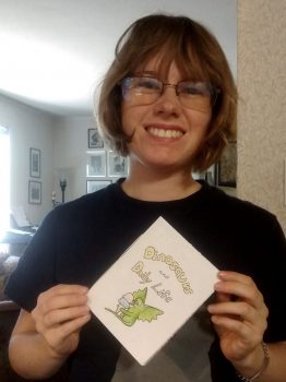 Hannah Adams holding her zine "Dinosaurs & Daily Life"