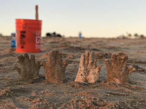 4 plaster hands sitting on the sand at Seal Beach, CA