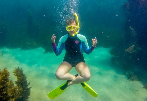 Chantae Reden in a wetsuit and with snorkel gear, underwater, in a lotus pose