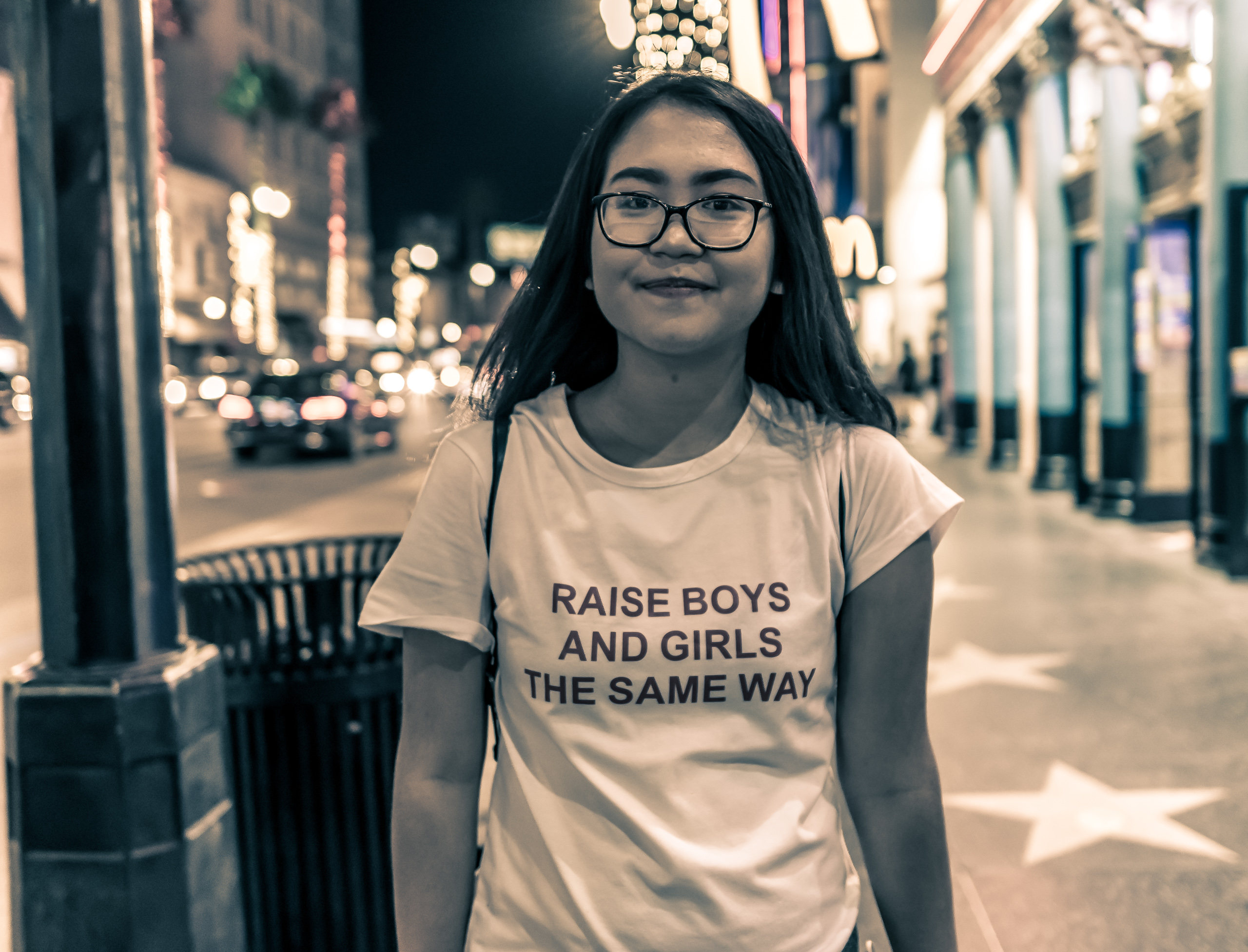 a woman on Hollywood Blvd wearing a t-shirt that reads "Raise Boys and Girls the Same Way"