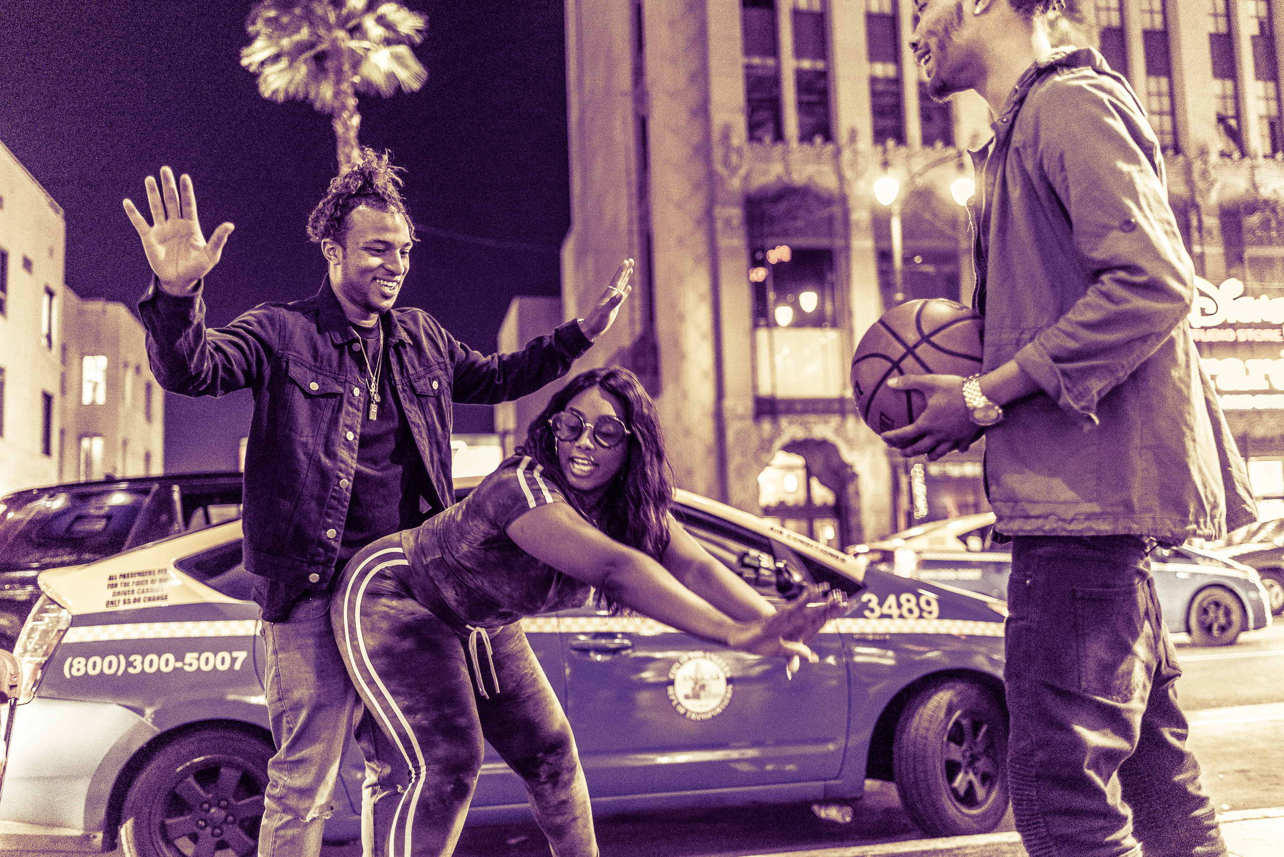 a woman and two men play basketball on the sidewalk on Hollywood Blvd. 