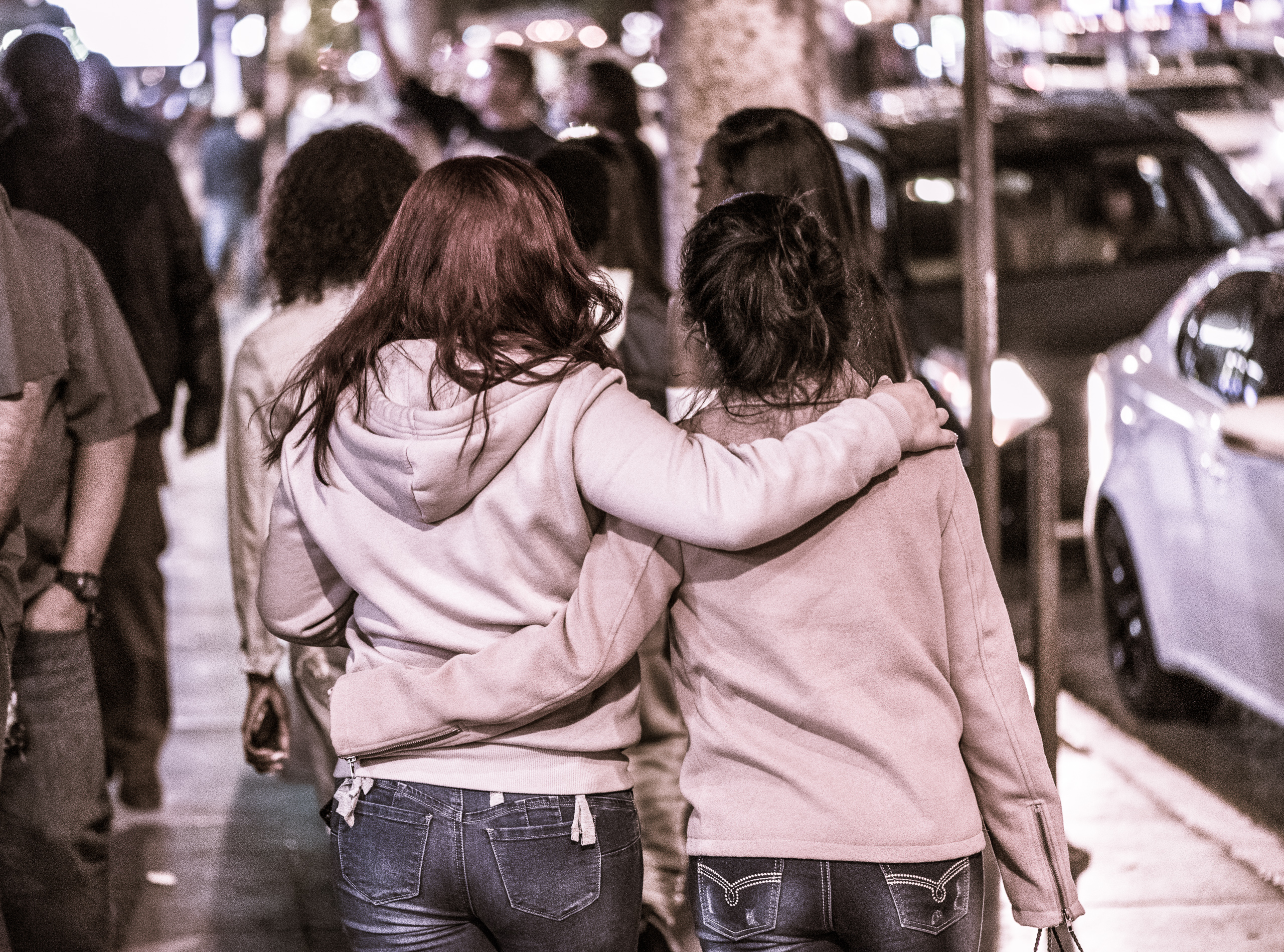 two women walk down the street arm-in-arm