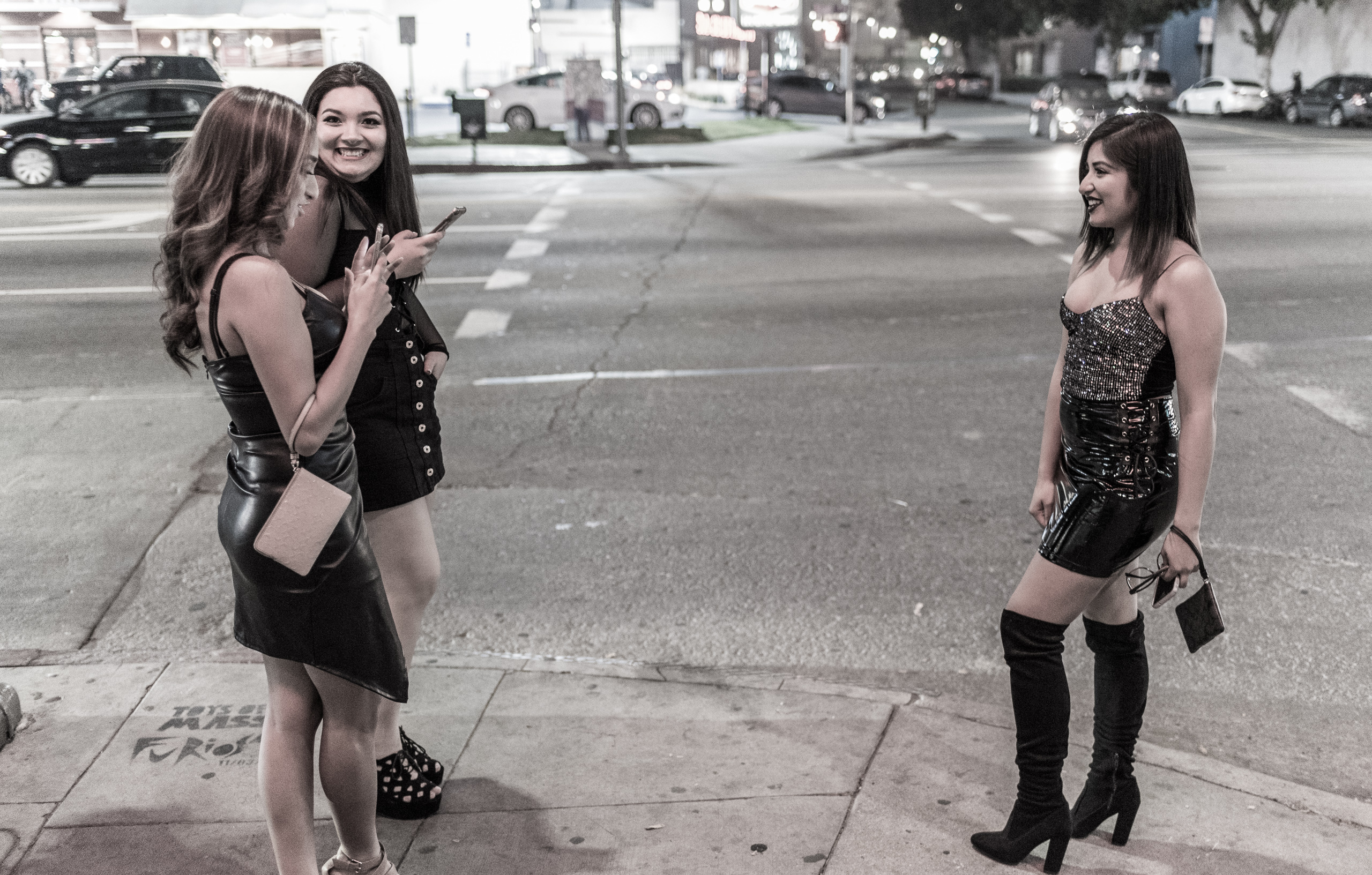 On the corner of Sunset & Ivar in Hollywood, a girl poses for her 2 friends who take her picture with their cell phones