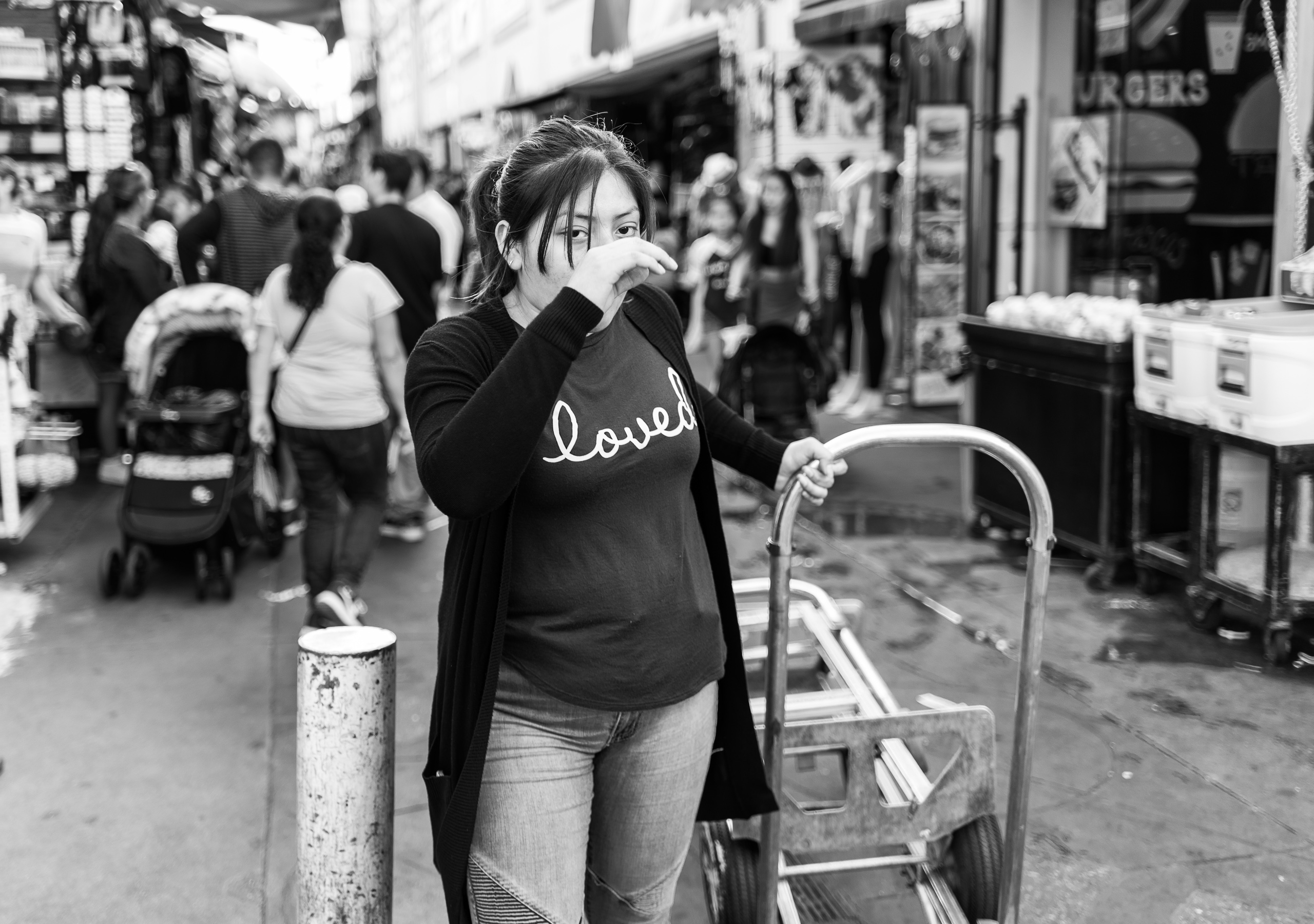 a woman wheeling a dolly and wearing a "loved" t-shirt in Santee Alley, Garment District, Los Angeles, CA