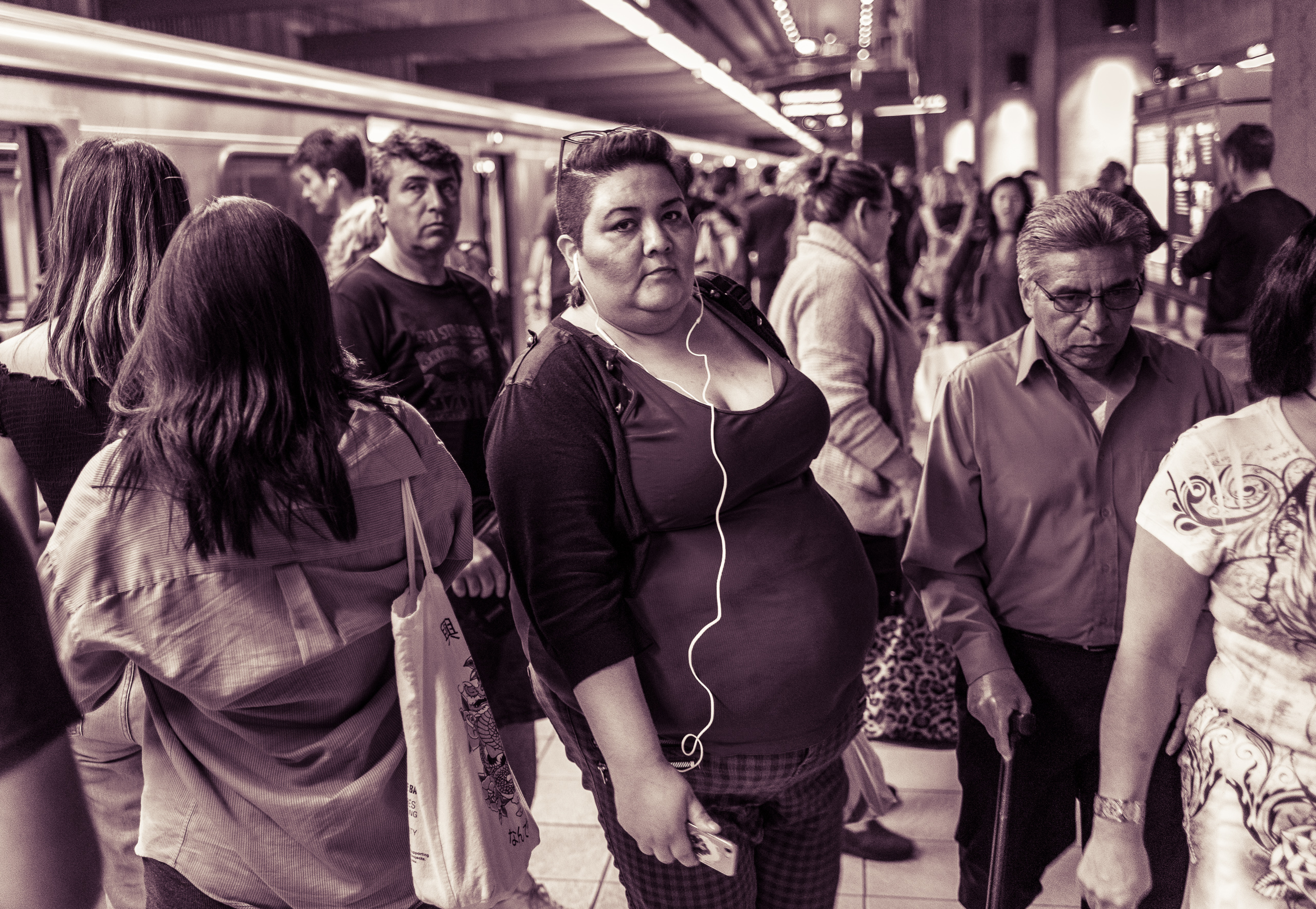 a woman with a white earbud cord dangling in front of her moves through a crowd exiting a Red Line train on the platform at Union Station in Downtown Los Angeles