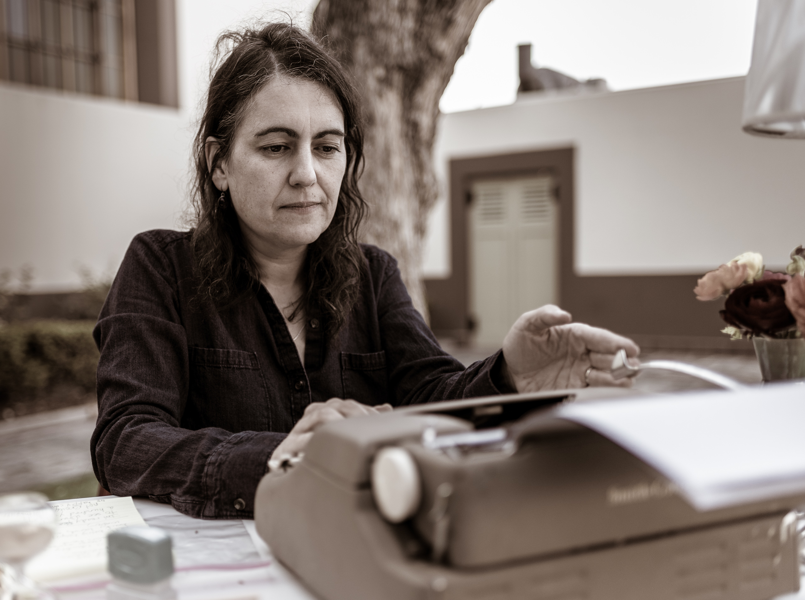 Poet Lory Bedikian at a typewriter on a table on the grass of Union Station's North Patio on the occasion of "The Poet Is In", and event celebrating National Poetry Month.