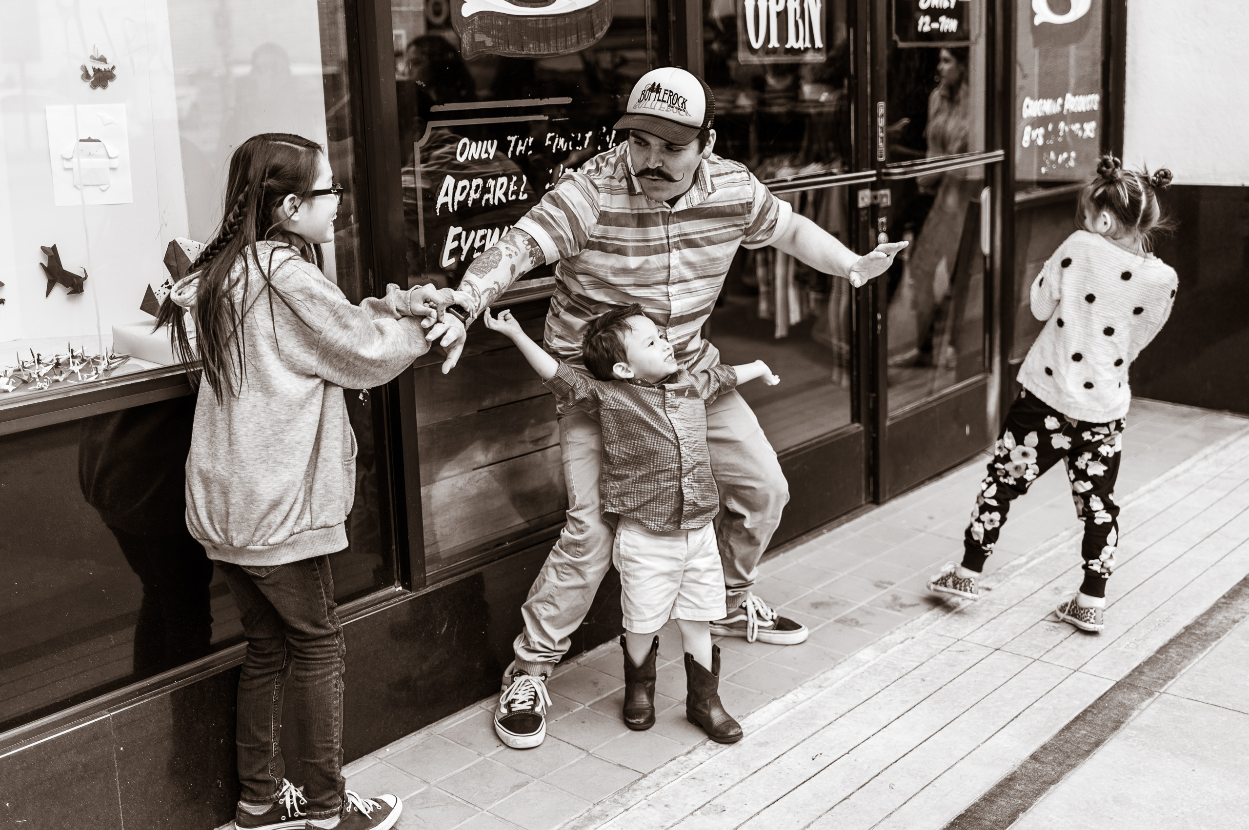 a man and 3 children play a game in front of a shop in Little Tokyo, Los Angeles, CA