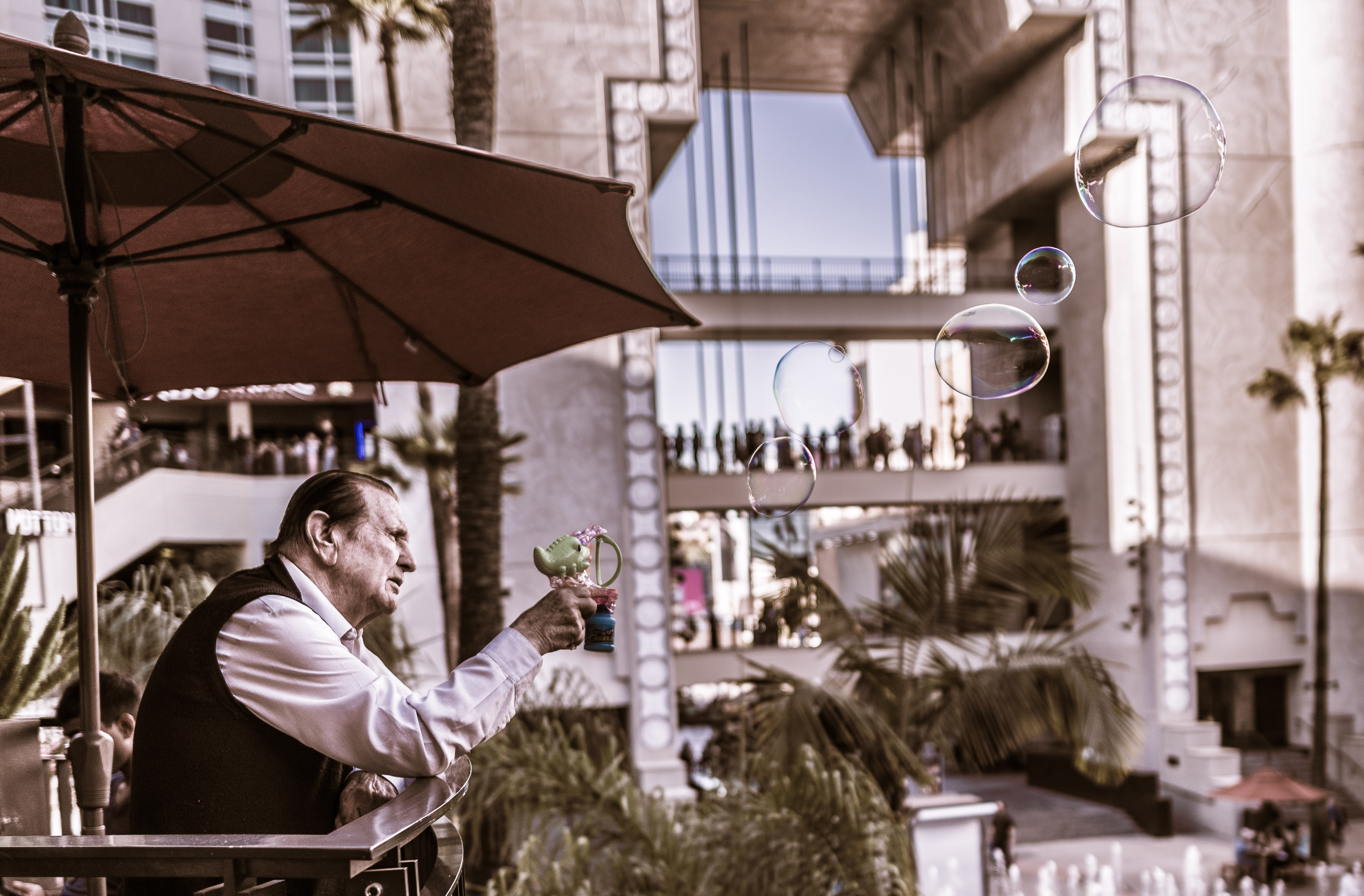 an old man blows large soap bubbles off a balcony at the Hollywood & Highland Center in Hollywood, Los Angeles, California