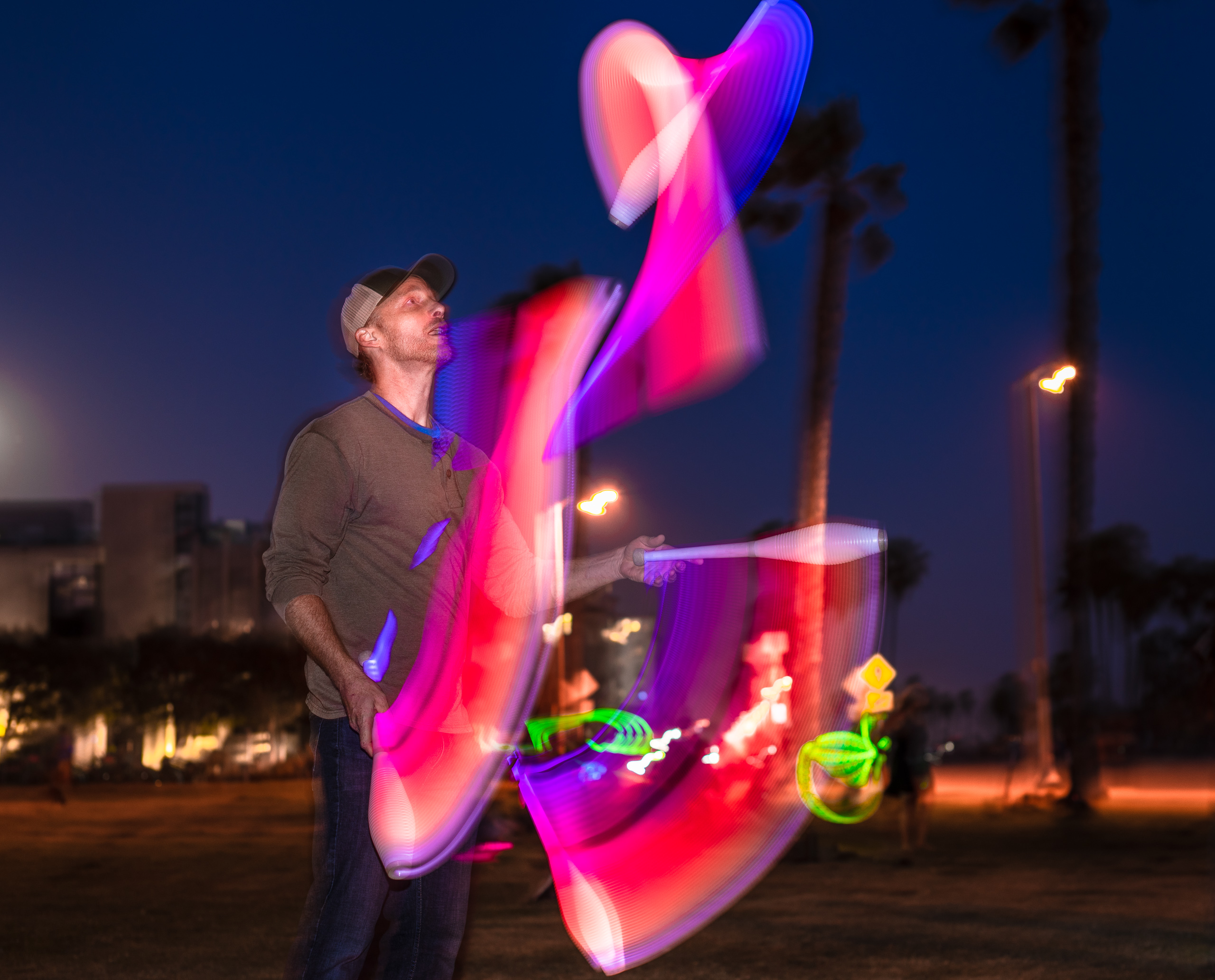 Morgan Bennett juggling LED Clubs in the dark at Venice Glow Flow in Venice Beach, CA