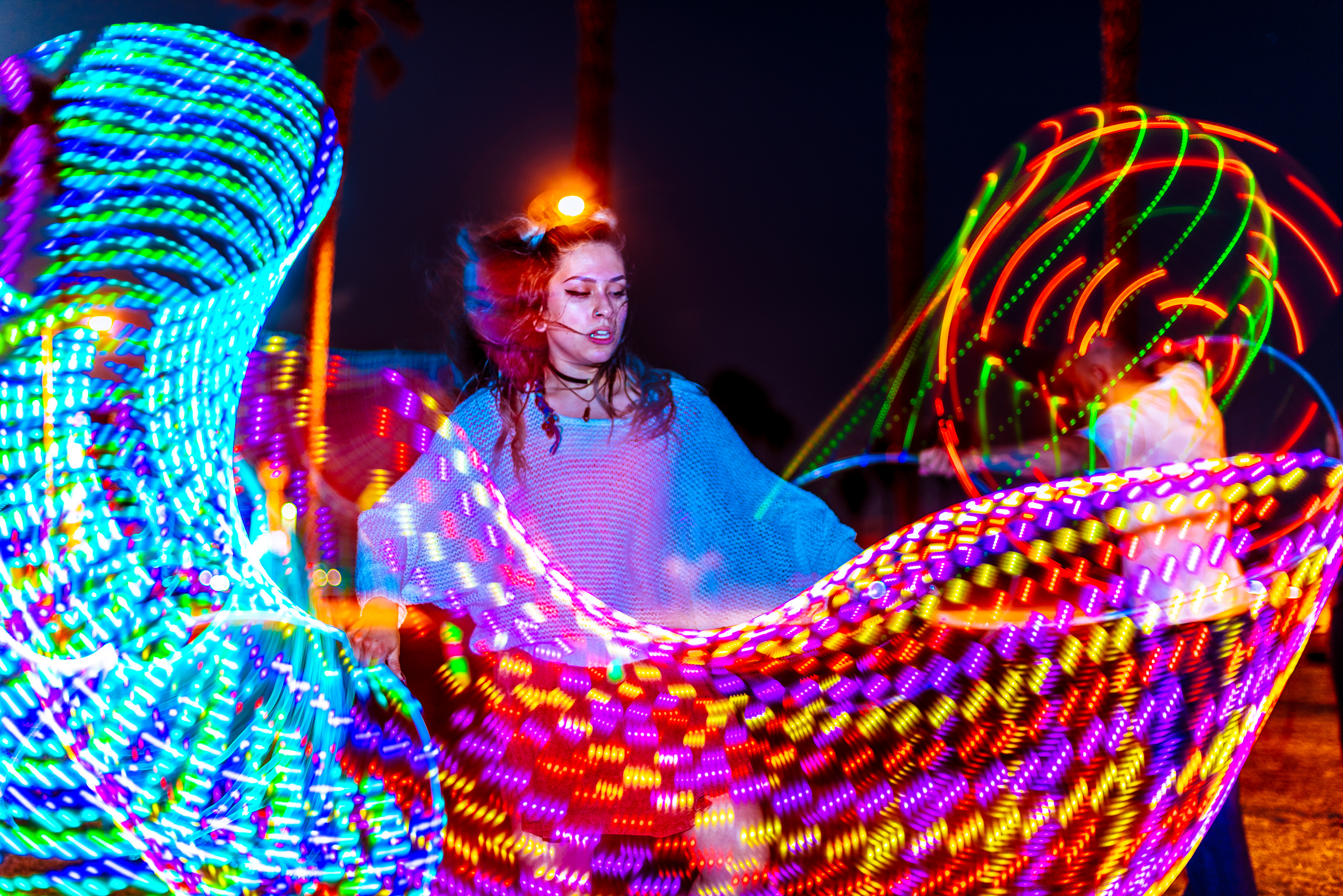 Alli Wolf, aka @wolfamongweeds, Los Angeles based DJ, Producer, Flow Artist, Techno, dancing with an LED hoop at Venice Glow Flow in the park at Venice Beach, CA