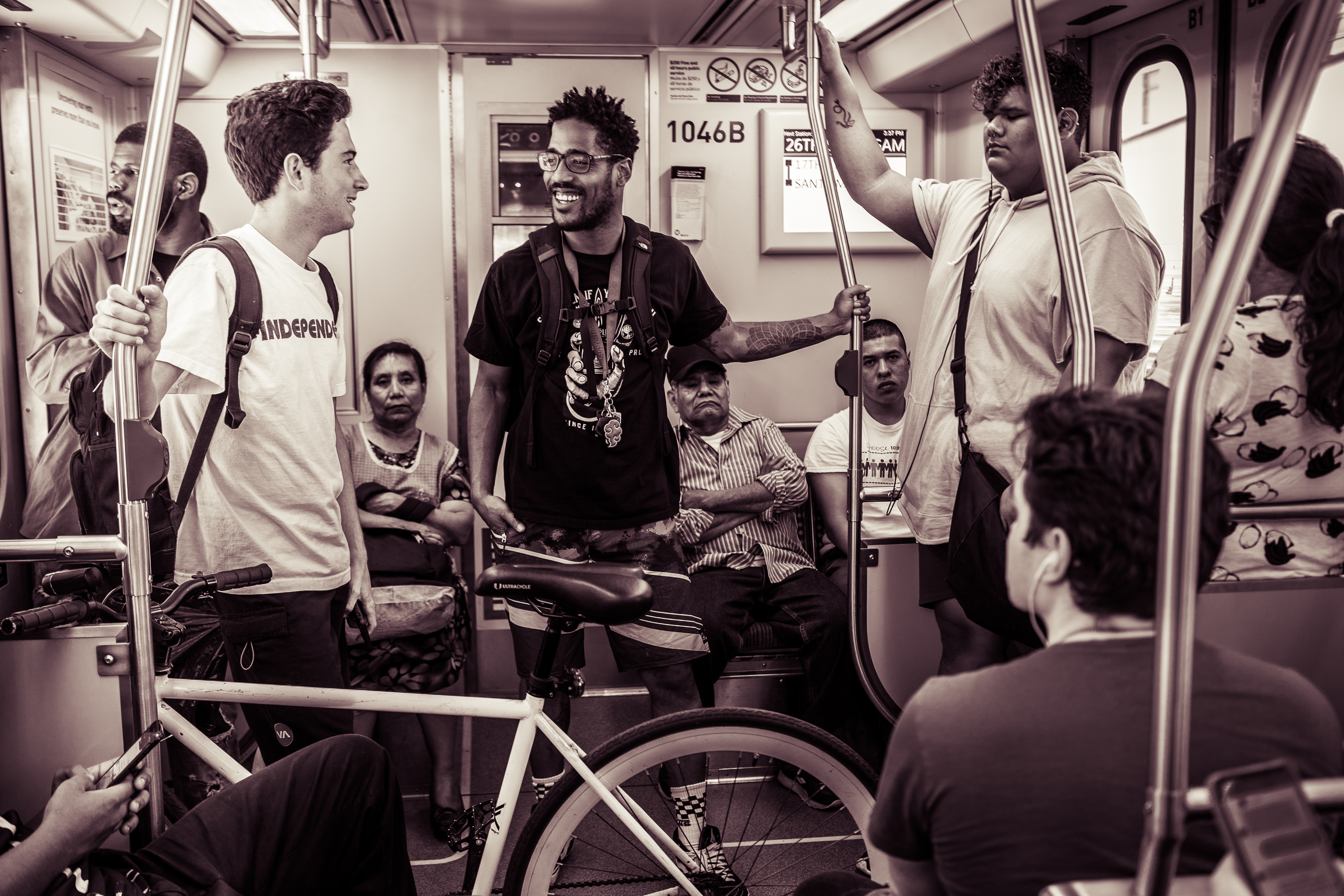 two guys with bicycles talk on a Metro train, one wears a t-shirt that reads "Independent"