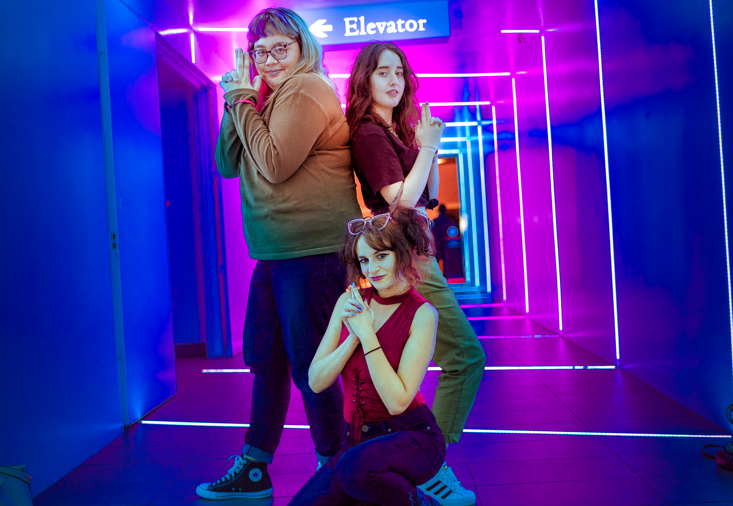 three women pose "like Charlie's Angels" in a neon-lit corridor in Little Tokyo in Los Angeles