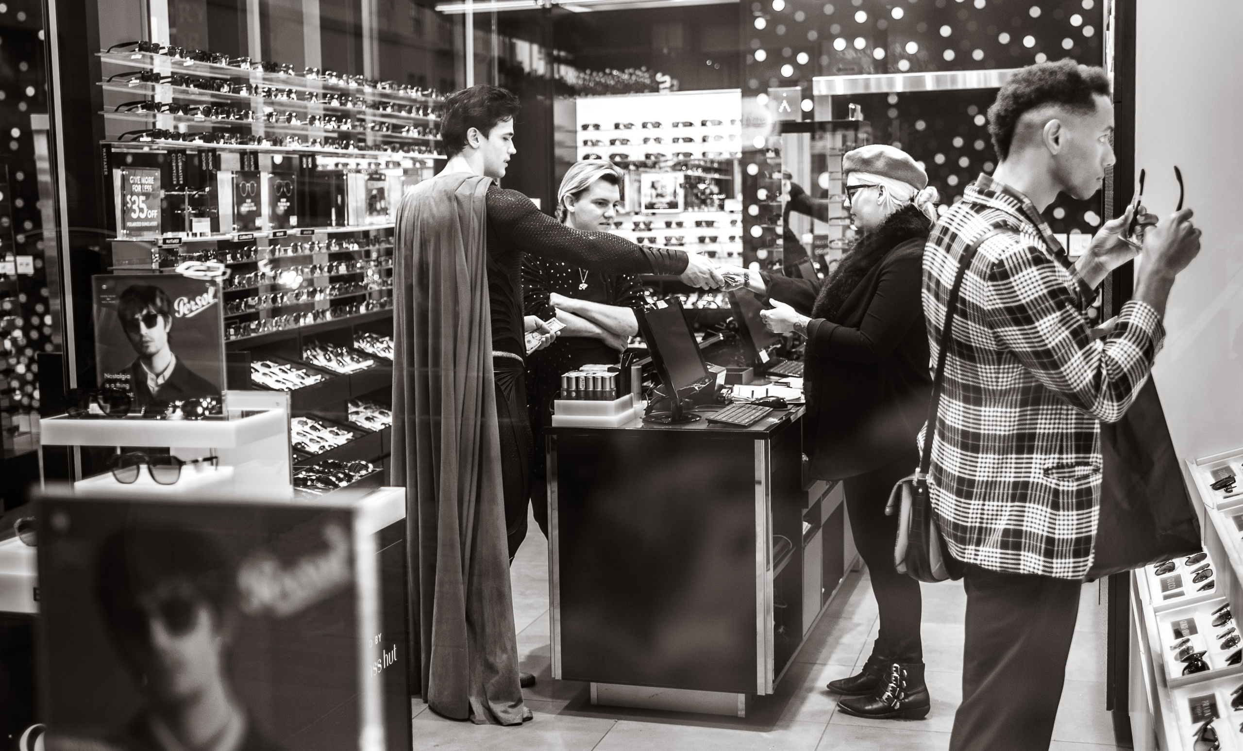Superman character on Hollywood Blvd inside a sunglasses shop making a transaction with the clerk there