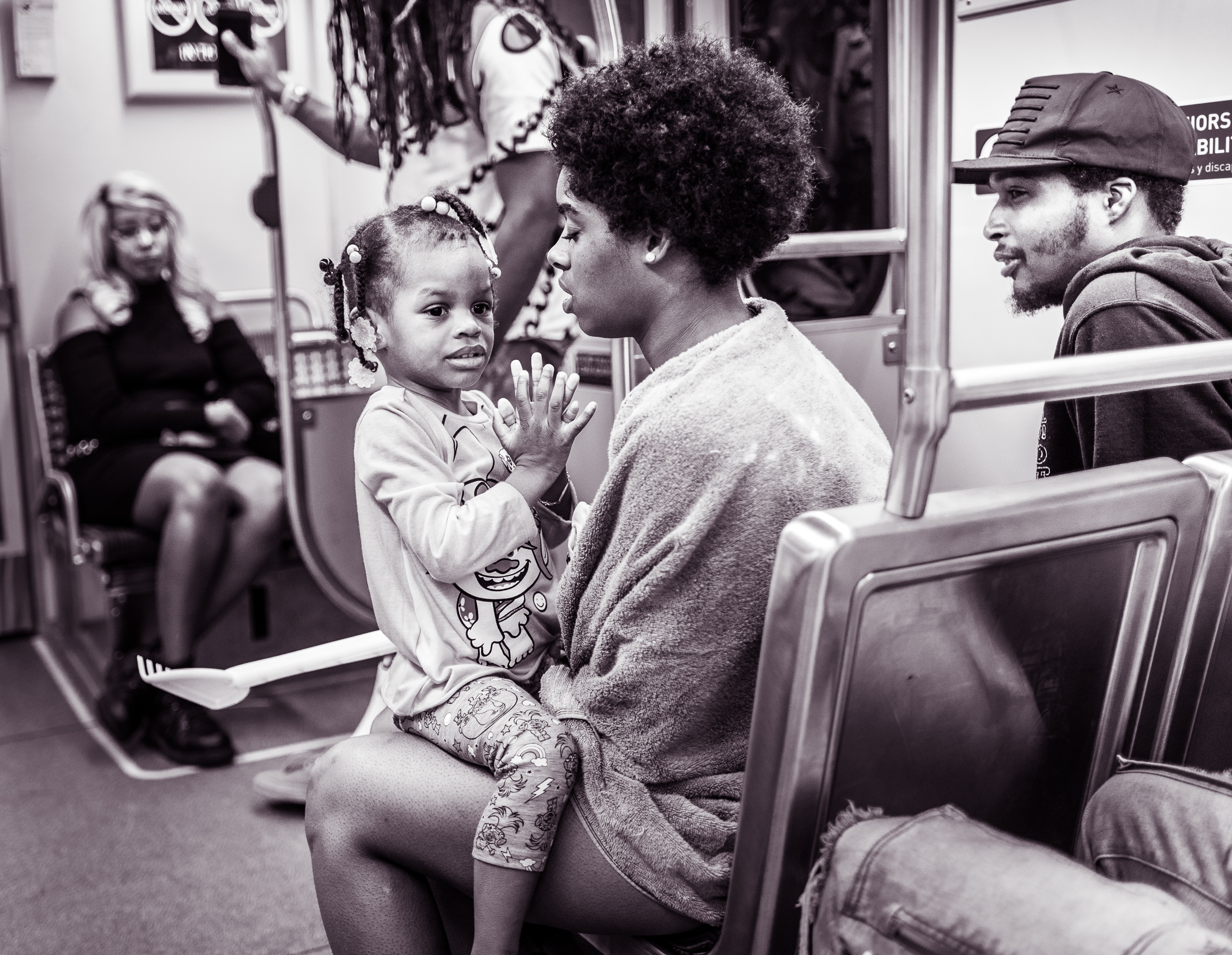 a young woman sits in an LA Metro Expo Line car with her child sitting on her lap facing her