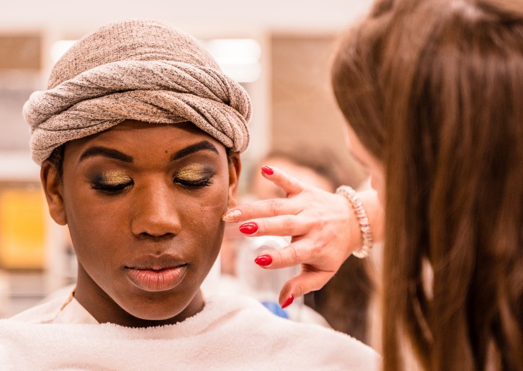 Kaia Cobb, 34, From Houston, Texas, Applies Makeup To Skye Johnson, 18, A Brooklyn, NY Born, And Raleigh, NC Raised, Student In The SMC Esthetician Program At The SMC Cosmetology Salons In The Business Building On SMC’s Main Campus On Thursday, April 18, 2019. In Addition To The Esthetician Program, Johnson Is Also Taking His Nursing Prerequisites At SMC With The Goal Of Becoming A Medical Aesthetician. Medical Aestheticians Provide Skin Care In Medical Settings And Can Assist With Injectables Like Botox. Cobb Holds A 2007 BBA In Economics From Baylor University In Waco, Texas. She Enrolled In The Esthetician Program At SMC To Pursue Her "Teenage Dream Of Being A Makeup Artist In Los Angeles." (Glenn Zucman/The Corsair)