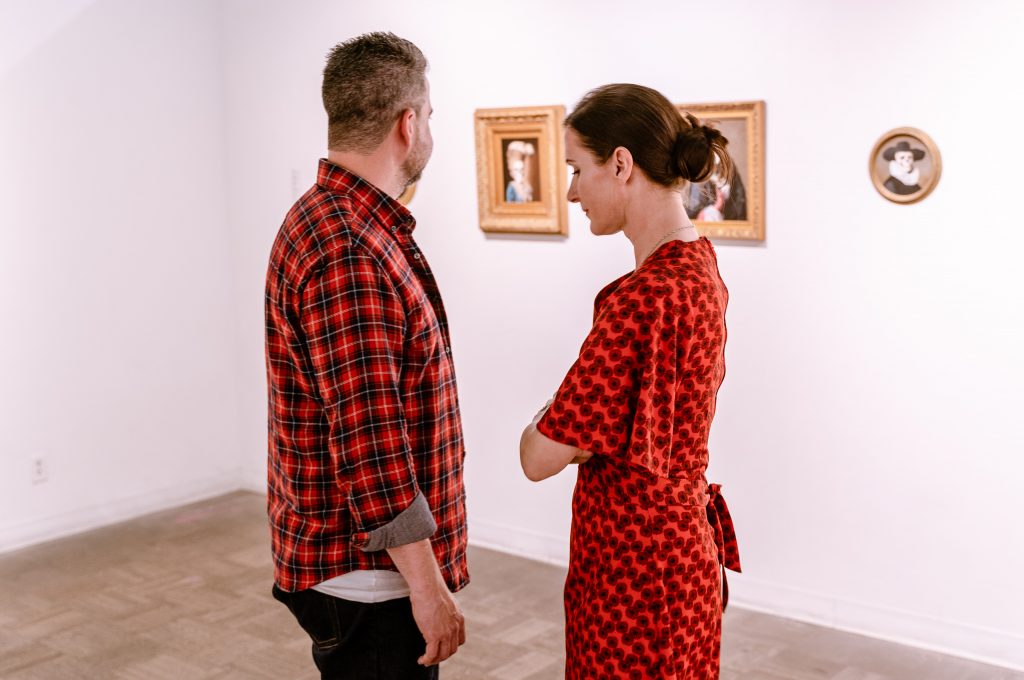 Artist And Illustrator Michele Melcher (Right), And Her Husband Brian Isserman, A Creative Director In Brand Design, From Carversville, Pennsylvania, Share A Quiet Moment In Front Of Her Paintings At The Opening Of Onward, A Group Portrait Show That Features Four Of Melcher's Intimate, Neo-Baroque Portraits In Precious Victorian Frames, At La Luz De Jesus Gallery In Los Angeles On Friday, May 3, 2019. Two Shows Are Running At La Luz De Jesus From May 3 To June 2: Matthew Couper's Solo Exhibition In Memory Of Water, And The Group Portrait Show Onward Featuring Artists Michele Melcher, Baldur Helgason, Yeo Kaa, Valery Pobjoy, And Sung Jik Yang. (Glenn Zucman/The Corsair)