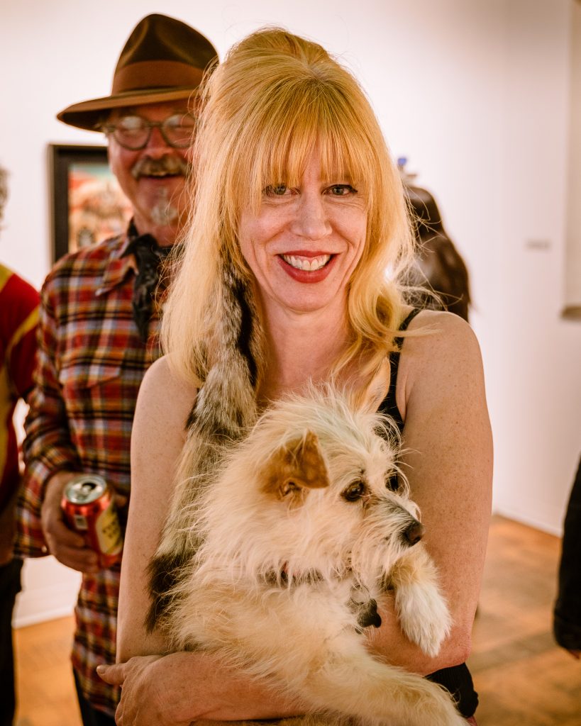 Owner-Instructor At Glendale Yoga, Laura Bogner, Holds La Luz De Jesus Gallery Owner Billy Shire's Dog "Floyd Shire" At The Opening Of In Memory Of Water And Onward At Shire's La Luz De Jesus Gallery In Los Angeles On Friday, May 3, 2019. Behind Bogner Is Her Husband Mark Johnson, Who Manages Vacation Rentals In Joshua Tree. Two Shows Are Running At La Luz De Jesus From May 3 To June 2: Matthew Couper's Solo Exhibition In Memory Of Water, And The Group Portrait Show Onward Featuring Artists Michele Melcher, Baldur Helgason, Yeo Kaa, Valery Pobjoy, And Sung Jik Yang. (Glenn Zucman/The Corsair)