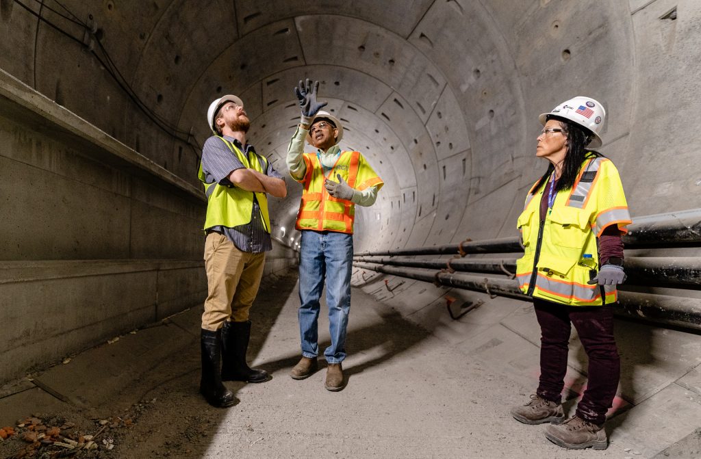 Walking Through The Half-Mile-Long Tunnel That Will Connect Metro Rail’s Future Little Tokyo/Arts District Station To Its Future Historic Broadway Station, Regional Connector Director Of Construction Management Rajni Patel (Center) Explains The Project To Corsair Staff Writer Michael Fanelli (Left). They Are Accompanied By Regional Connector Senior Safety Manager Michelle Jones (Right) As They Walk Underneath 2nd Street In Downtown Los Angeles On Wednesday, April 3, 2019. When Completed In 2022, The Regional Connector Will Simplify East-West And North-South Transportation In Los Angeles. For Example, To Travel From East Los Angeles College To Santa Monica College Currently Takes 3 Trains, But Will Only Require One Train In 2022. (Glenn Zucman/The Corsair)