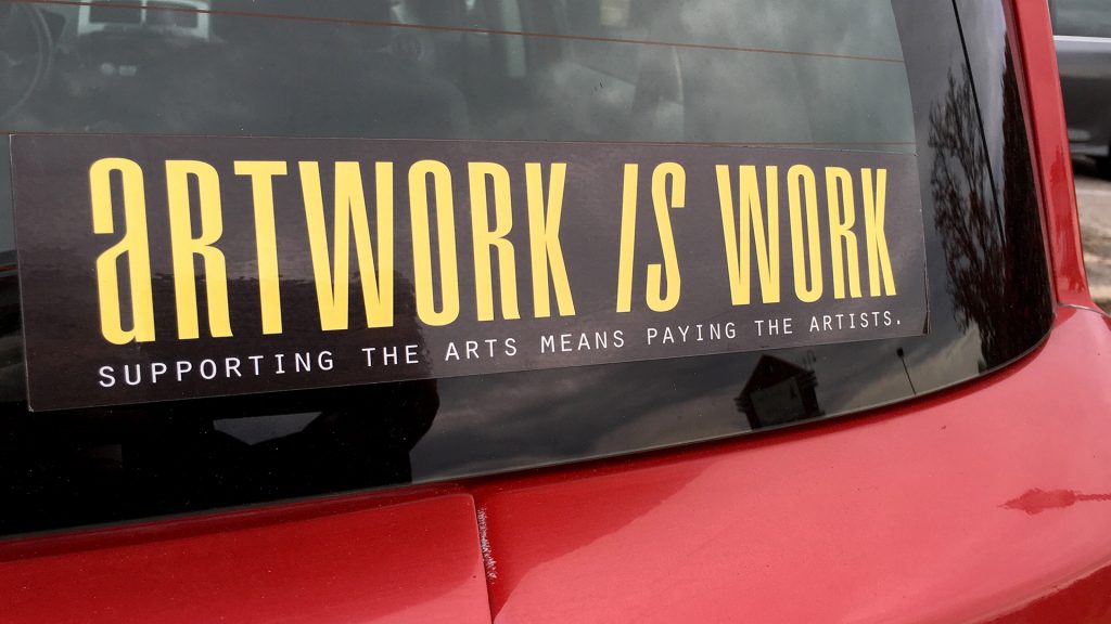 photo of a car with a sticker on the window that reads, "Artwork is work"