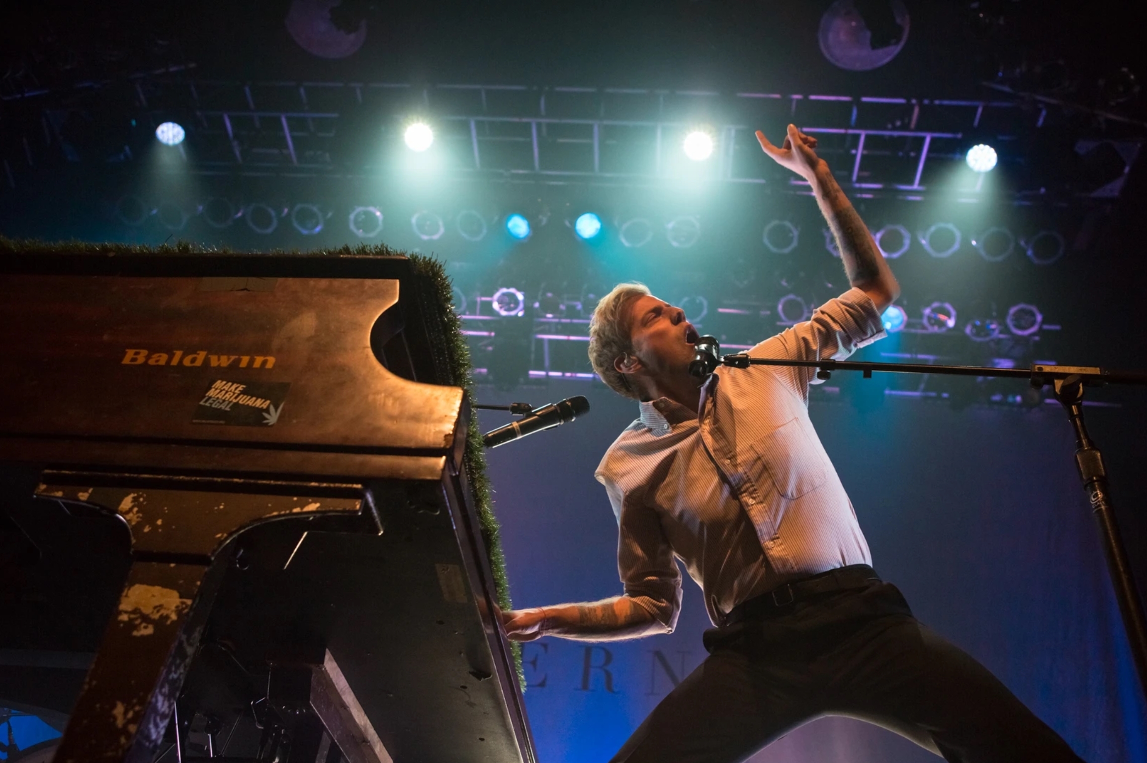 Photo of Andrew McMahon performing at a piano and gesturing boldly into the sky.